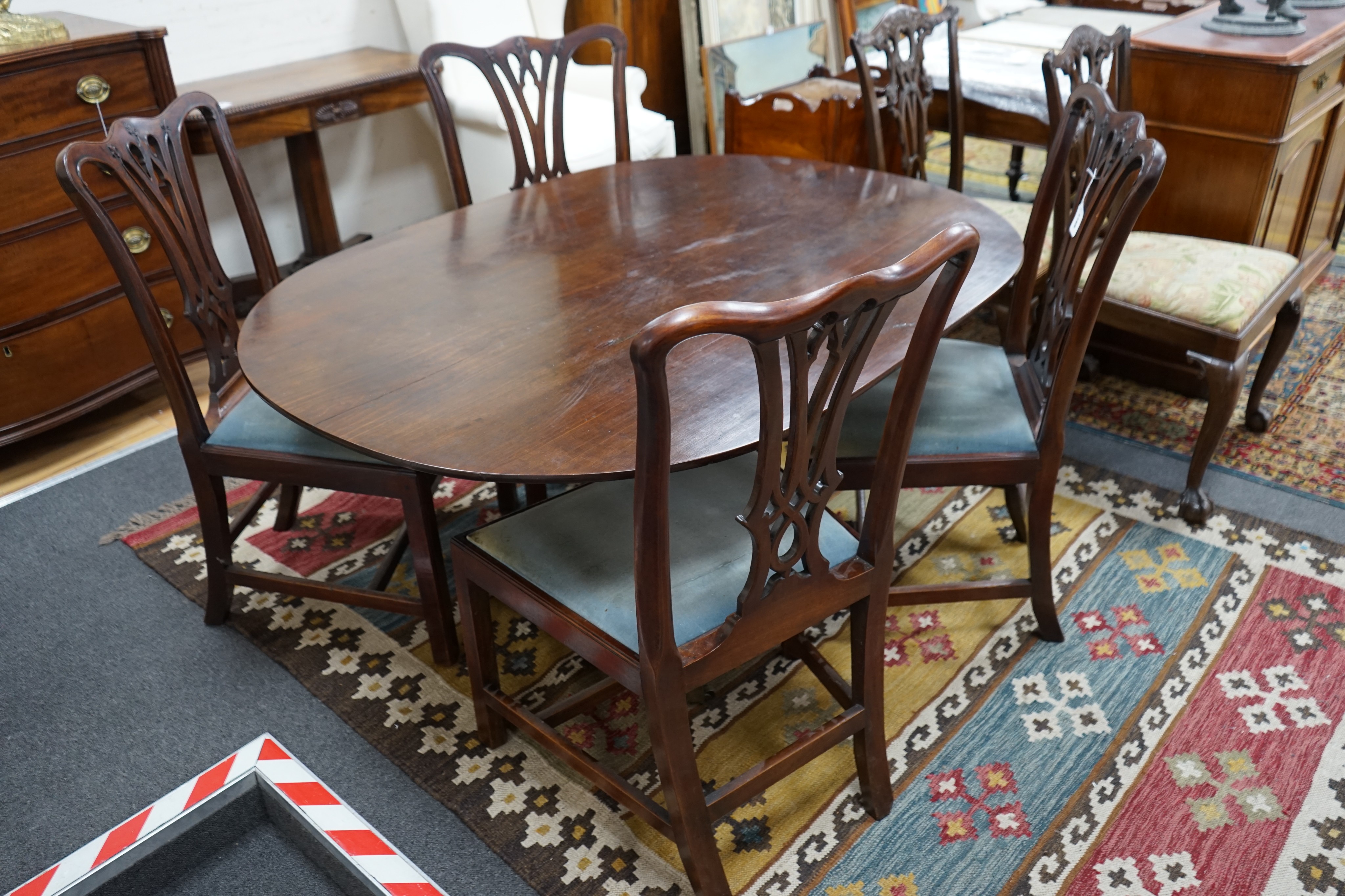 A George III oval mahogany tilt top dining table, altered, width 146cm, depth 106cm, height 69cm together with four George III mahogany dining chairs